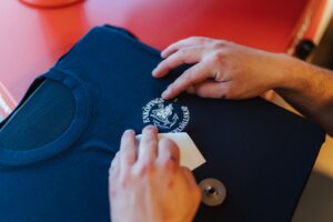 Fingrar som drar bort och viras trycket på en tröja till Enköpings seglarsällskap